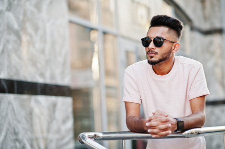 Stylish indian beard man at sunglasses and pink t-shirt. India model posed outdoor at streets of city.の写真素材