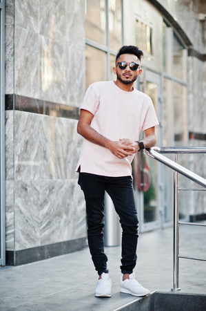Stylish indian beard man at sunglasses and pink t-shirt. India model posed outdoor at streets of city.の写真素材