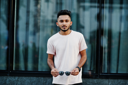 Stylish indian beard man at pink t-shirt, sunglasses. India model posed outdoor at streets of city.の写真素材