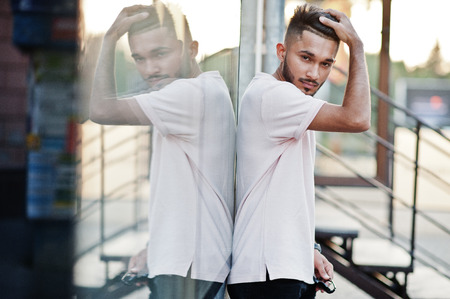 Stylish indian beard man at pink t-shirt. India model posed outdoor at streets of city against mirror of window.の写真素材