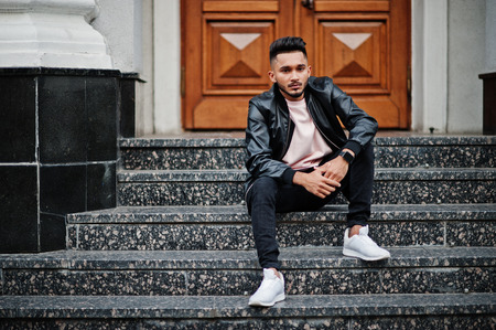 Stylish indian beard man at black leather jacket. India model posed sitting at streets of city.の写真素材