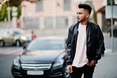 Stylish indian beard man at black leather jacket against car. India model posed at streets of city.の写真素材