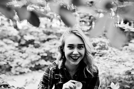 Portrait of an attractive blond girl posing with a compass in a forest.