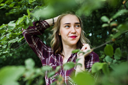 Close-up portrait of a smiling blond girl in tartan shirt in the countryside.の写真素材
