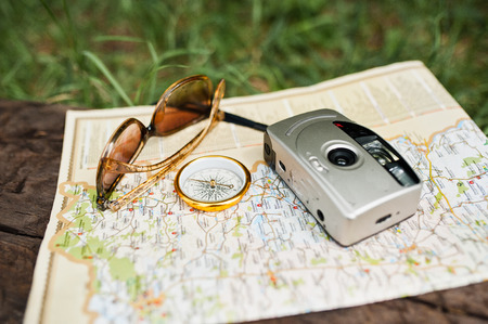 Close-up photo of compass laying on the map next to the camera and sunglasses.の写真素材