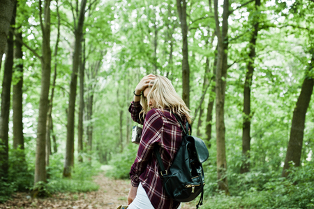Portrait of a young beautiful blond woman in tartan shirt holding a map in the forest.の写真素材