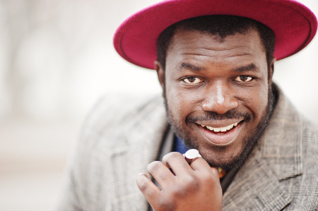 Close up portrait of stylish African American man model in gray coat, jacket tie and red hat.の写真素材