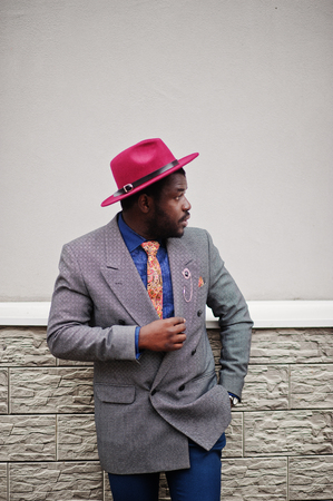Stylish African American man model in gray jacket tie and red hat.