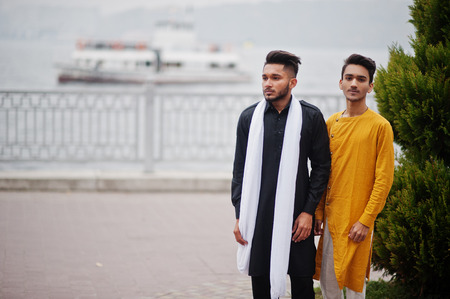 Two indian stylish mans friends in traditional clothes posed outdoor against steamboat on sea.の写真素材