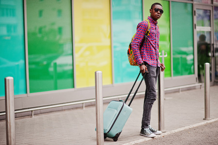 African american man in checkered shirt, sunglasses and jeans with suitcase. Black man traveler.の写真素材