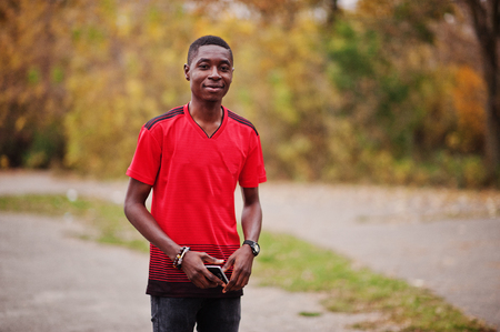 African american man in red football sport t-shirt against autumn park.の写真素材