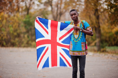 African man in africa traditional shirt on autumn park with Great Britain flag.の写真素材