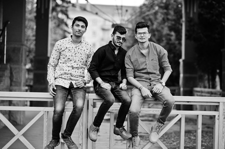 Three indian guys students friends sitting on street. Black and white photo.の写真素材