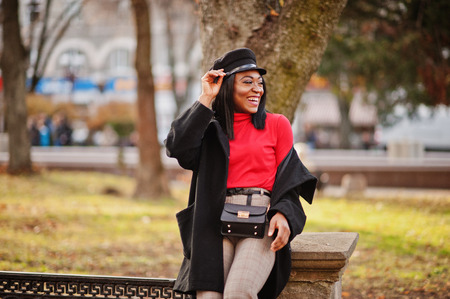 African american fashion girl in coat and newsboy cap posed at street.の写真素材