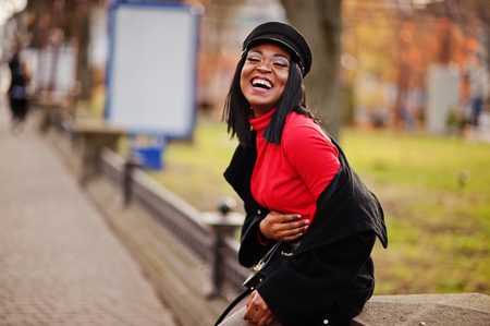 African american fashion girl in coat and newsboy cap posed at street.の写真素材