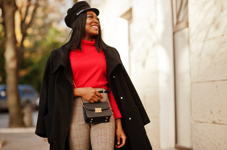 African american fashion girl in coat and newsboy cap posed at street.の写真素材