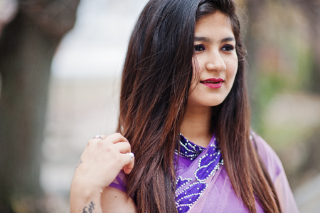 Close up portrait of indian hindu girl at traditional violet saree posed at street.の写真素材