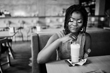 Attractive african american woman sitting at table on cafe with latte.