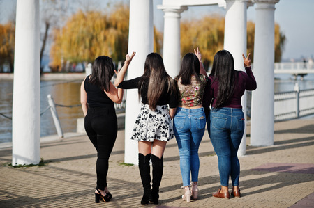 Back of group four happy and pretty latino girls from Ecuador posed at street.の写真素材