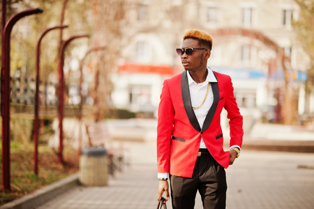 Fashion african american man model at red suit, with highlights hair and handbag posed at street.の写真素材