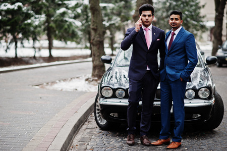 Two elegant indian fashionable mans model on suit posed at winter day against black classic car.の写真素材