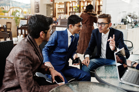 Group of three indian business man in suits sitting at office on cafe and looking at laptop.の写真素材