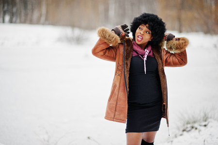 Curly hair african american woman wear on sheepskin coat and gloves posed at winter day.の写真素材