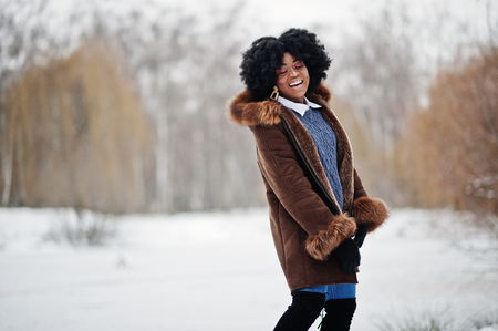 Curly hair african american woman wear on sheepskin coat and gloves posed at winter day.の写真素材