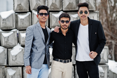 Group of three casual young indian mans in sunglasses posed against stone blocks.の写真素材