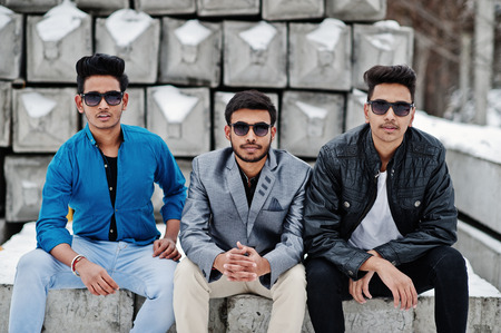 Group of three casual young indian mans in sunglasses posed against stone blocks.の写真素材
