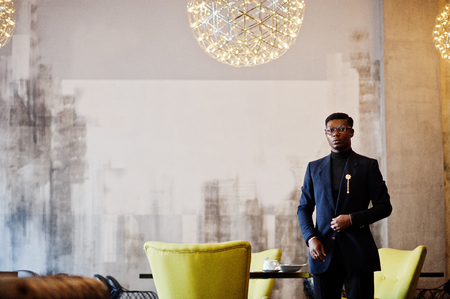 Fashionable african american man in suit and glasses posed at cafe.の写真素材