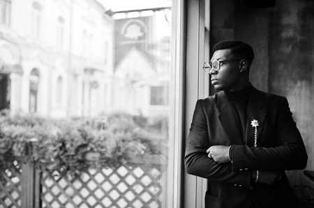 Fashionable african american man in suit and glasses posed at cafe.の写真素材