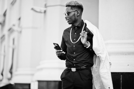 Chic handsome african american man in white suit and black shirt with mobile phone.の写真素材