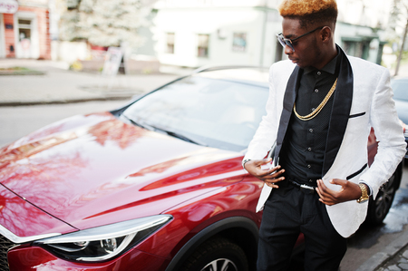 Chic handsome african american man in white suit against red luxury car.の写真素材