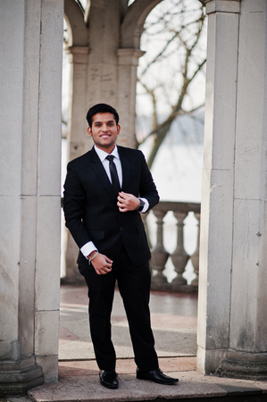 Elegant south asian indian business man in black suit standing under arch.の写真素材