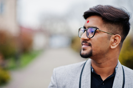 Close up head of stylish indian man with bindi on forehead and glasses, wear on suit posed outdoor.の写真素材