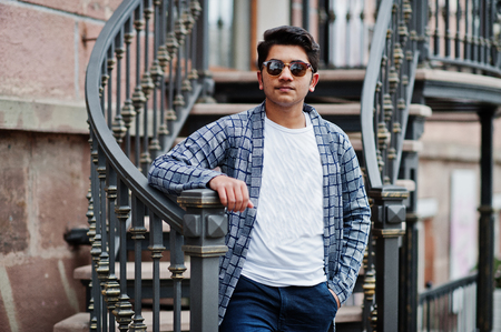 Stylish indian young man at sunglasses wear casual posed outdoor against iron stairs.の写真素材