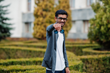 Stylish indian man at sunglasses wear casual posed outdoor and show double glass of glasses.の写真素材