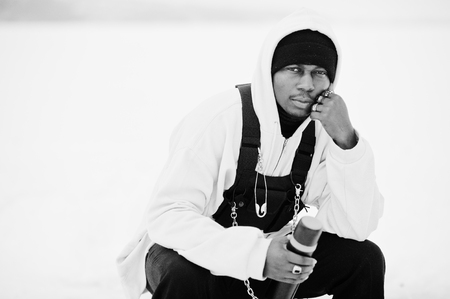 African american fisherman with bottle sitting on frozen lake. Winter fishing.の写真素材