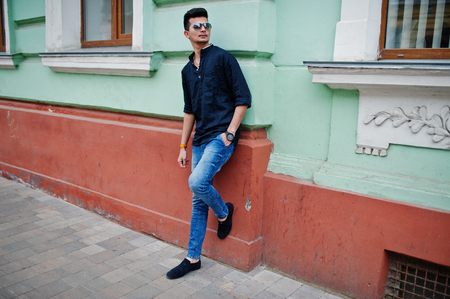 Stylish indian model man in casual clothes, black shirt and sunglasses posed outdoor at street of India.の写真素材