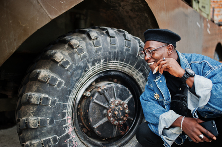 African american man in jeans jacket, beret and eyeglasses, smoking cigar and posedの写真素材