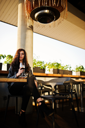 Young curly woman enjoying  her wine in a bar.の写真素材