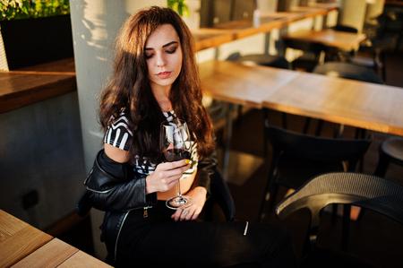 Young curly woman enjoying  her wine in a bar.の写真素材