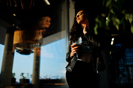 Young curly woman enjoying  her wine in a bar.の写真素材