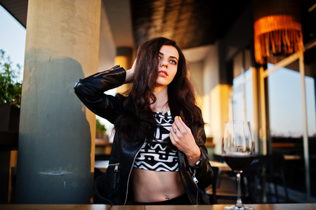 Young curly woman enjoying  her wine in a bar.の写真素材