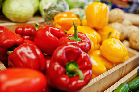 Colorful shiny fresh vegetables. Bell sweet yellow and red peppers on the shelf of a supermarket or grocery store.の写真素材