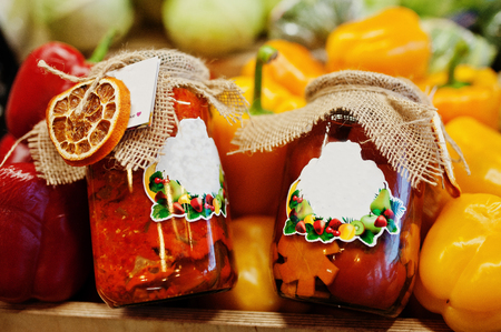 Two roasted pickled canning sweet pepper on jars at the shelf of a supermarket or grocery store.の写真素材