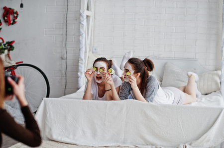 Close up back of young girl photographer shooting on studio two girls while they make their own masks cream . Professional photographer on work.の写真素材