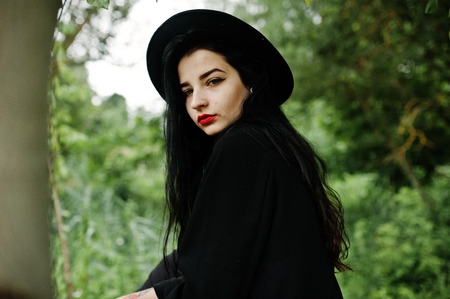 Sensual girl all in black, red lips and hat. Goth dramatic woman.