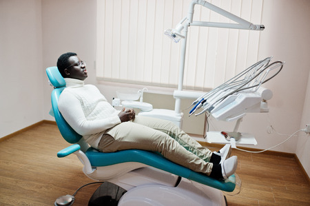 African american man patient in dental chair. Dentist office and doctor practice concept.の写真素材